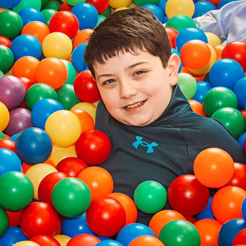 boy in a colorful ball pit smiling